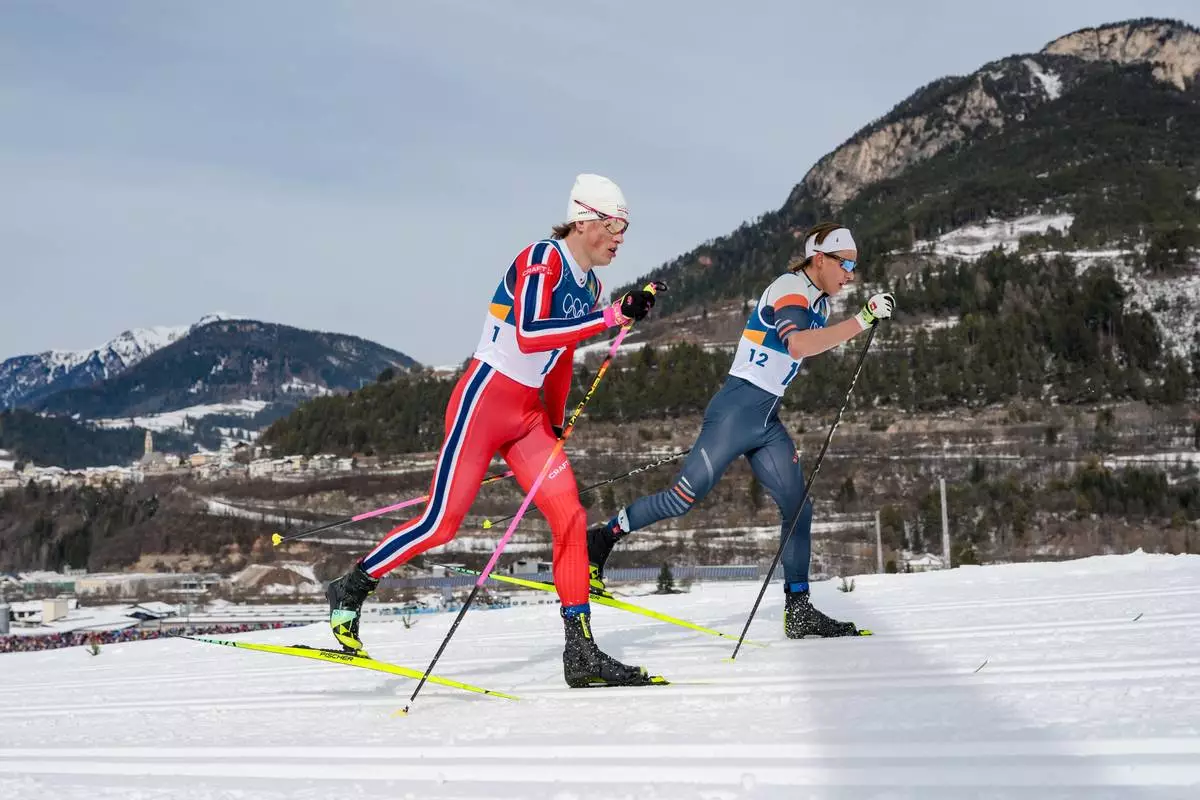 Johannes Hoesflot Klaebo, of Norway, left, and Individual Neutral Athlete Savelii Korostelev compete in the cross country skiing men's 50km mass start Classic at the 2026 Winter Olympics, in Tesero, Italy, Saturday, Feb. 21, 2026. (AP Photo/Evgeniy Maloletka)