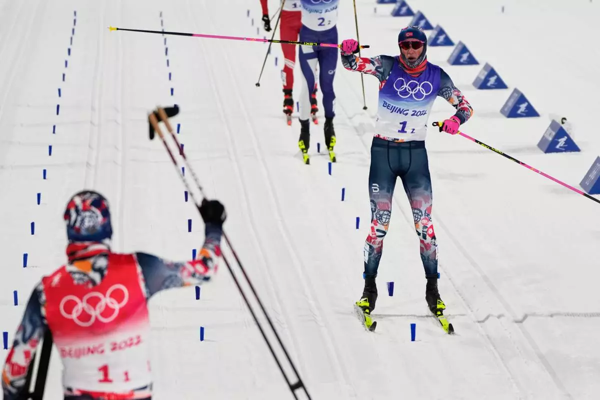 FILE- Johannes Hoesflot Klaebo, of Norway, right, celebrates as he nears the finish with Erik Valnes, of Norway, left, during the men's team sprint classic cross-country skiing competition at the 2022 Winter Olympics, Feb. 16, 2022, in Zhangjiakou, China. (AP Photo/Alessandra Tarantino, File)