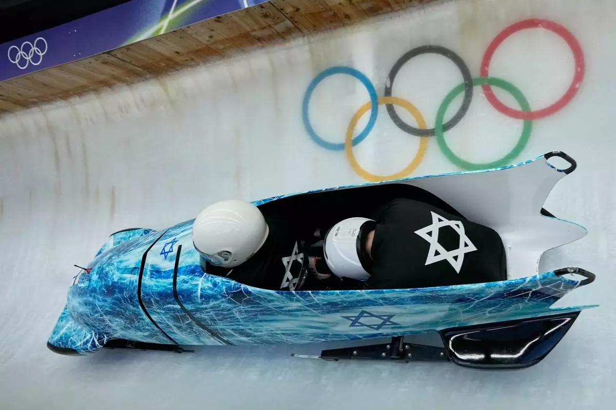 Israel's Adam Edelman, left, slides down the track during a two man bobsled training session at the 2026 Winter Olympics, in Cortina d'Ampezzo, Italy, Friday, Feb. 13, 2026. (AP Photo/Aijaz Rahi)
