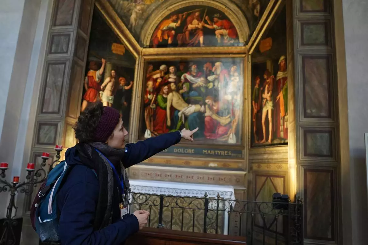 Sara Cainarca, a volunteer with the “La Via della Bellezza,” or “The Path of Beauty,” initiative, gestures toward a fresco inside the Basilica of San Lorenzo Maggiore in Milan, Italy, Wednesday, Feb. 18, 2026. (AP Photo/María Teresa Hernández)