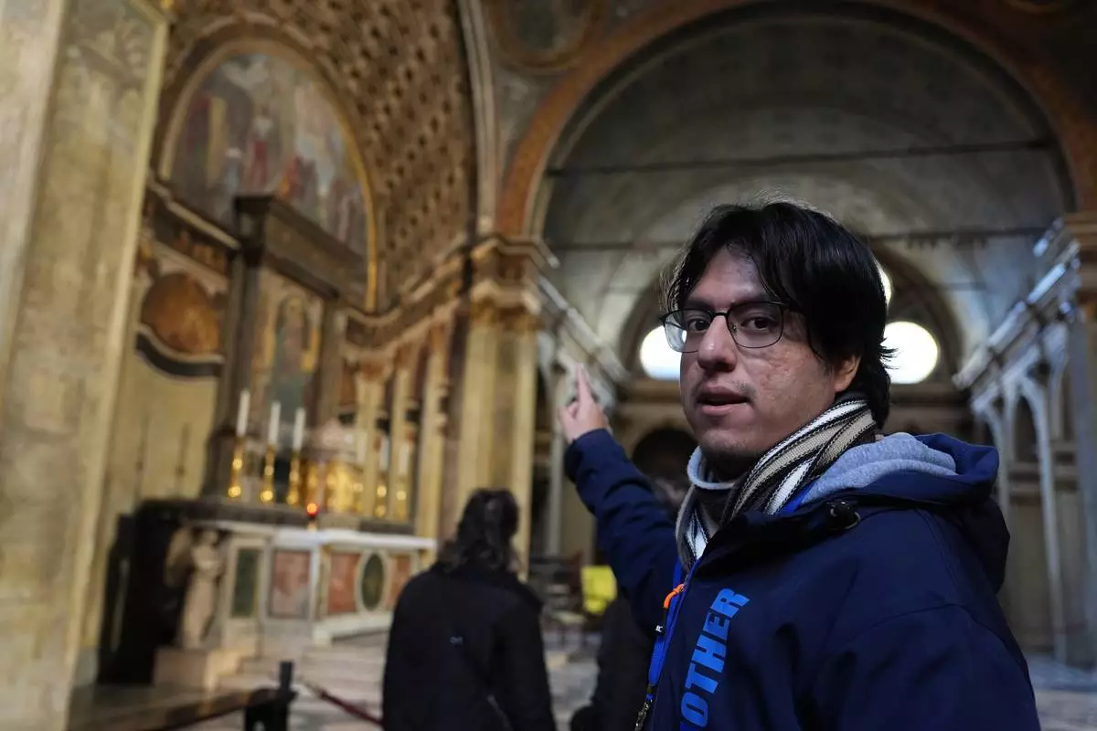 Víctor Ortiz, a volunteer with the “La Via della Bellezza,” or “The Path of Beauty,” initiative, gestures toward artwork inside the church of Santa Maria presso San Satiro in Milan, Italy, Wednesday, Feb. 18, 2026. (AP Photo/María Teresa Hernández)