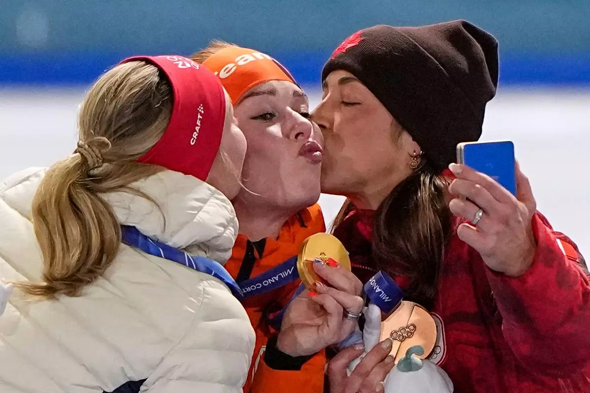 Antoinette Rijpma-de Jong of the Netherlands, center and gold medal, Ragne Wiklund of Norway, left and silver medal, and Valerie Maltais of Canada, right and bronze medal, celebrate on the podium of the women's 1500 meters speedskating race at the 2026 Winter Olympics, in Milan, Italy, Friday, Feb. 20, 2026. (AP Photo/Ben Curtis)
