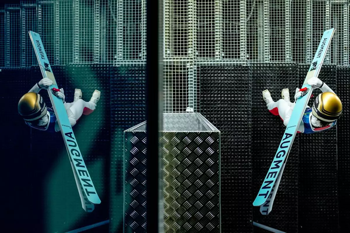 Lisa Eder, of Austria, is reflected on a window while getting ready to jump during a ski jumping, women's normal hill, training session, at the 2026 Winter Olympics, in Predazzo, Italy, Thursday, Feb. 5, 2026. (AP Photo/Matthias Schrader)