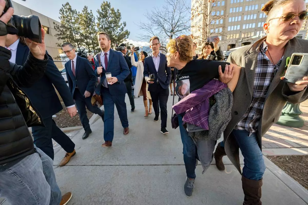 FILE - Chrystina Page, right, holds back Heather De Wolf, as she yells at Jon Hallford, left, the owner of Back to Nature Funeral Home, as he leaves with his lawyers following a preliminary hearing, Feb. 8, 2024, outside the El Paso County Judicial Building, in Colorado Springs, Colo. (Christian Murdock/The Gazette via AP, File)