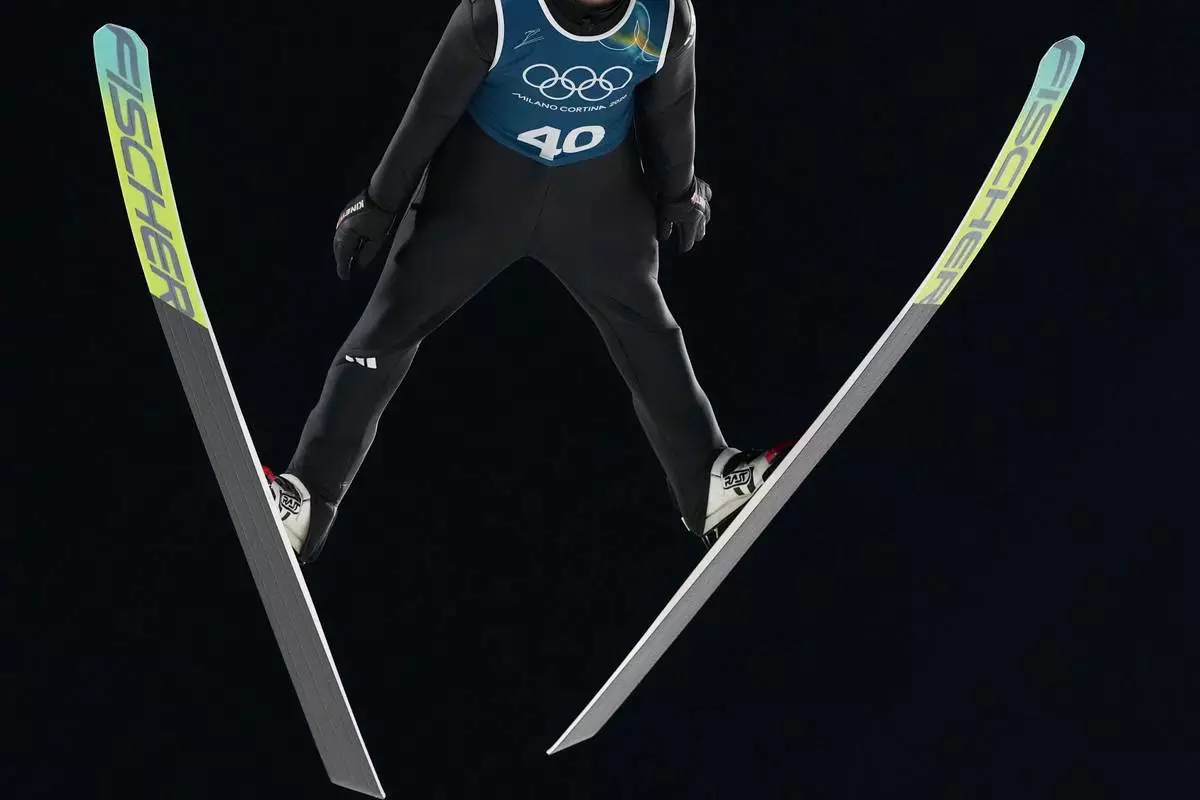 An athlete soars through the air during a ski jumping, men's normal hill, training session,at the 2026 Winter Olympics, in Predazzo, Italy, Thursday, Feb. 5, 2026. (AP Photo/Kirsty Wigglesworth)