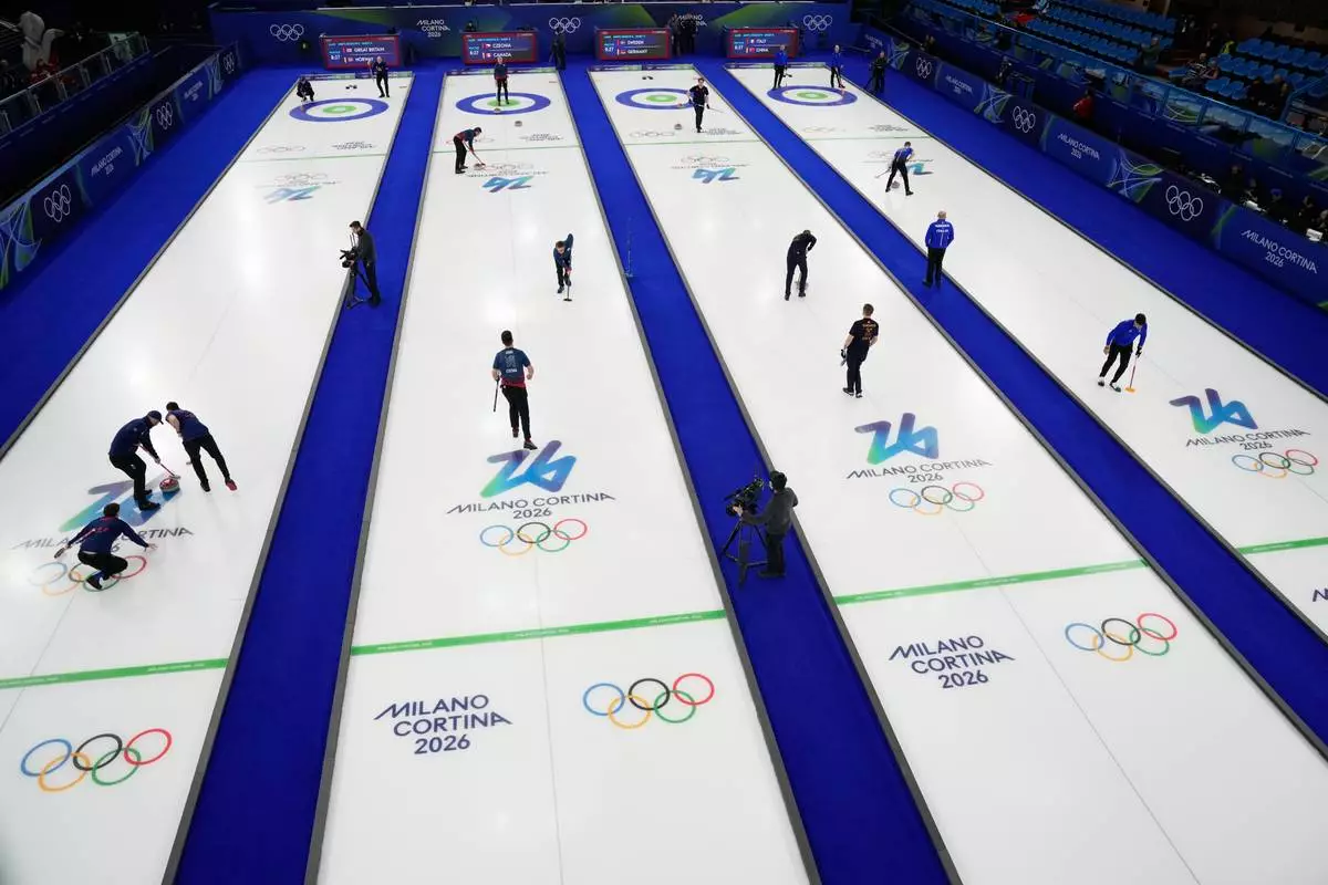 Athletes warm up before the start of a men's curling round robin session at the 2026 Winter Olympics, in Cortina d'Ampezzo, Italy, Monday, Feb. 16, 2026. (AP Photo/David J. Phillip)