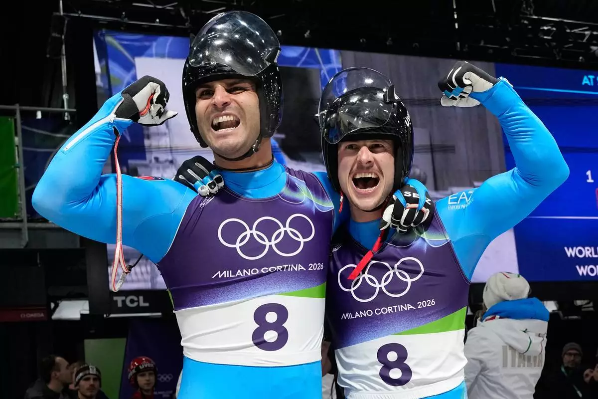 Italy's gold medalists Emanuel Rieder, left, and Simon Kainzwaldner, right, celebrate as they arrive at the finish during a men's doubles luge run at the 2026 Winter Olympics, in Cortina d'Ampezzo, Italy, Wednesday, Feb. 11, 2026. (AP Photo/Alessandra Tarantino)