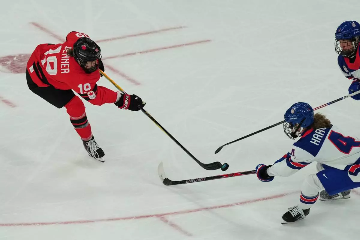 Canada's Brianne Jenner, left, challenges for the puck with United States' Caroline Harvey during a preliminary round match of women's ice hockey between USA and Canada at the 2026 Winter Olympics, in Milan, Italy, Tuesday, Feb. 10, 2026. (AP Photo/Antonio Calanni)