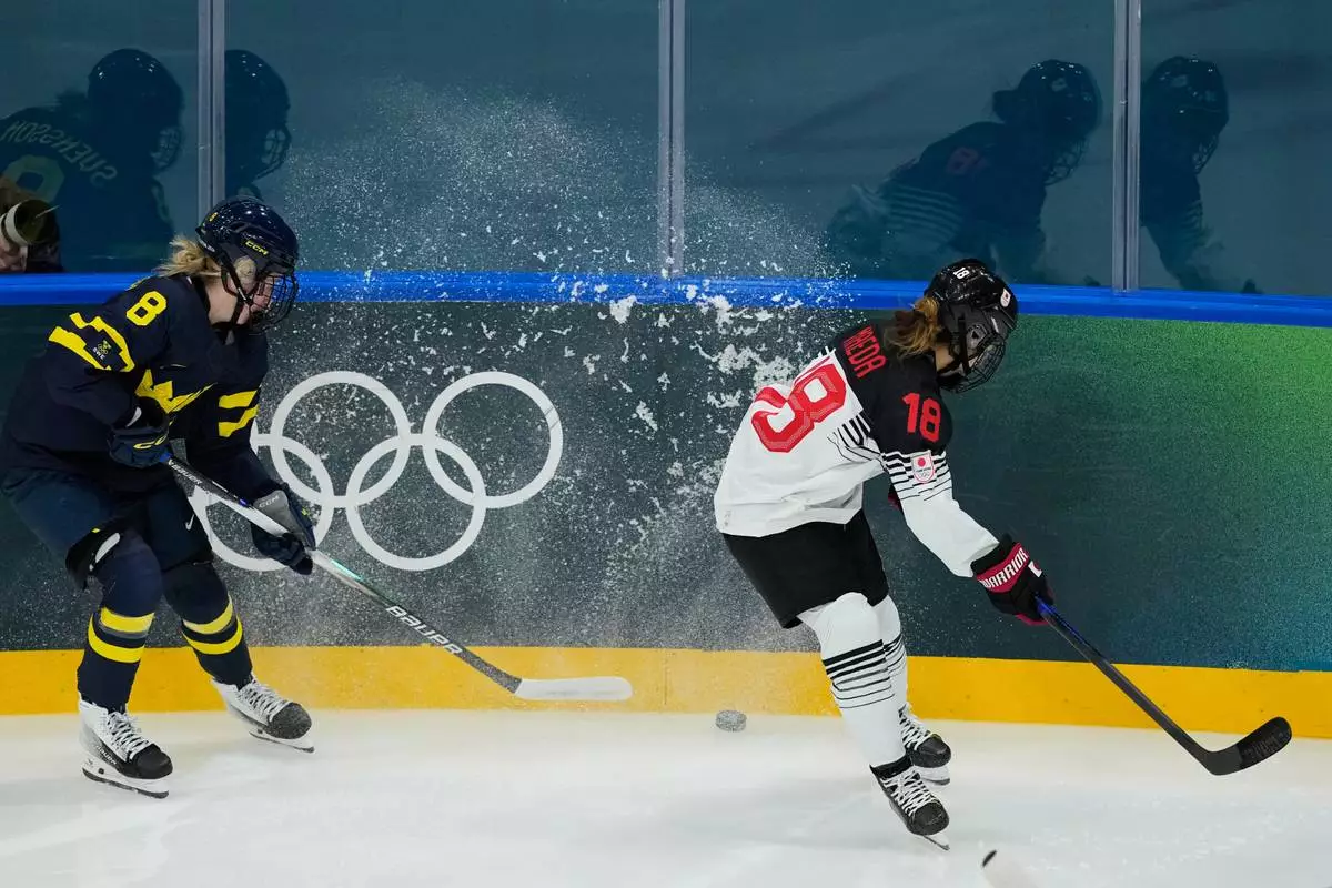 Japan's Suzuka Maeda, right, challenges Sweden's Hilda Svensson during a preliminary round match of women's ice hockey between Japan and Sweden at the 2026 Winter Olympics, in Milan, Italy, Tuesday, Feb. 10, 2026. (AP Photo/Hassan Ammar)