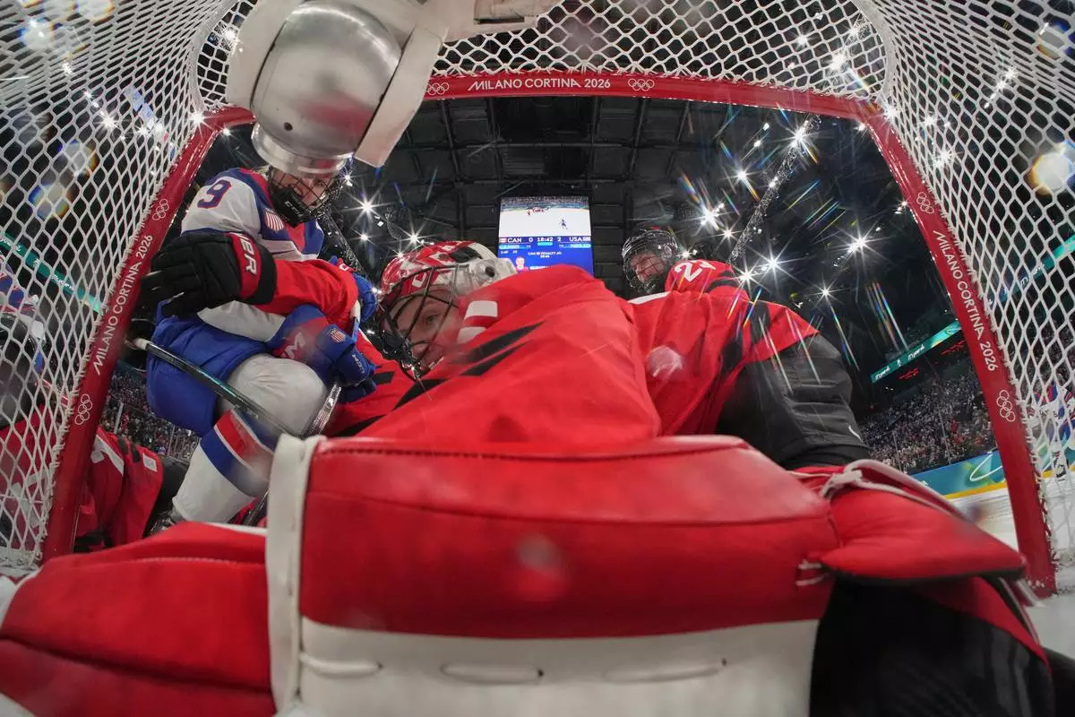 United States' Kirsten Simms, left, scores her side's third goal during a preliminary round match of women's ice hockey between Canada and the United States at the 2026 Winter Olympics, in Milan, Italy, Tuesday, Feb. 10, 2026. (Mike Segar/Pool Photo via AP)
