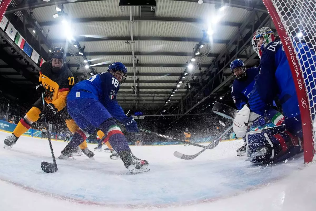 Germany's Emily Nix, left, scores her side's opening goal during a preliminary round match of women's ice hockey between Italy and Germany at the 2026 Winter Olympics, in Milan, Italy, Tuesday, Feb. 10, 2026. (AP Photo/Darko Bandic, Pool)