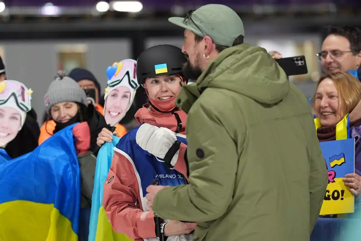 Ukraine's Kateryna Kotsar gets a proposal from Bogdan Fashtryga, front, as she competes in the women's freestyle skiing big air qualifications at the 2026 Winter Olympics, in Livigno, Italy, Saturday, Feb. 14, 2026. (AP Photo/Abbie Parr)