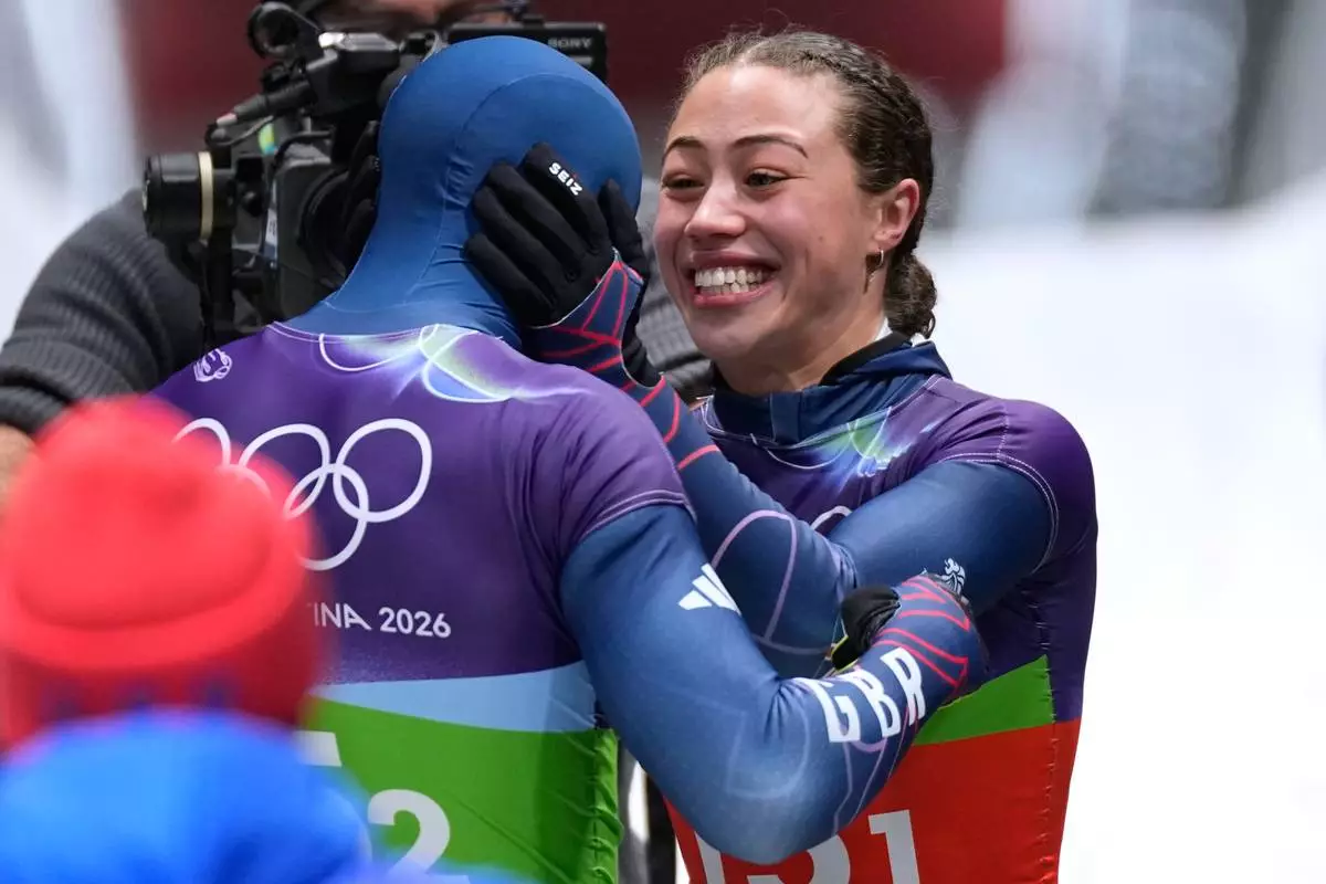 Britain's gold medalists Matt Weston, left, and Britain's Tabitha Stoecker, right, celebrate at the finish during the skeleton mixed team competition at the 2026 Winter Olympics, in Cortina d'Ampezzo, Italy, Sunday, Feb. 15, 2026. (AP Photo/Aijaz Rahi)