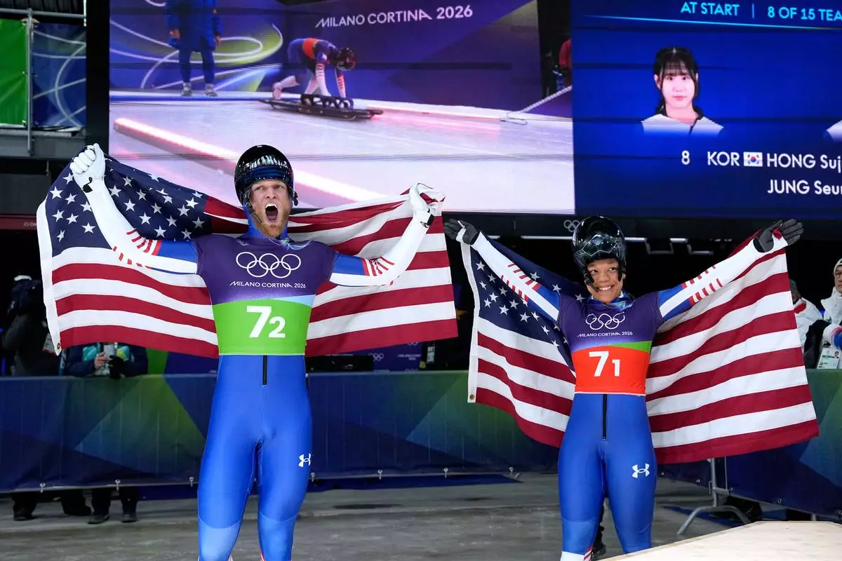 United States' Austin Florian, left, and United States' Mystique Ro celebrate at the finish during the skeleton mixed team competition at the 2026 Winter Olympics, in Cortina d'Ampezzo, Italy, Sunday, Feb. 15, 2026. (AP Photo/Alessandra Tarantino)