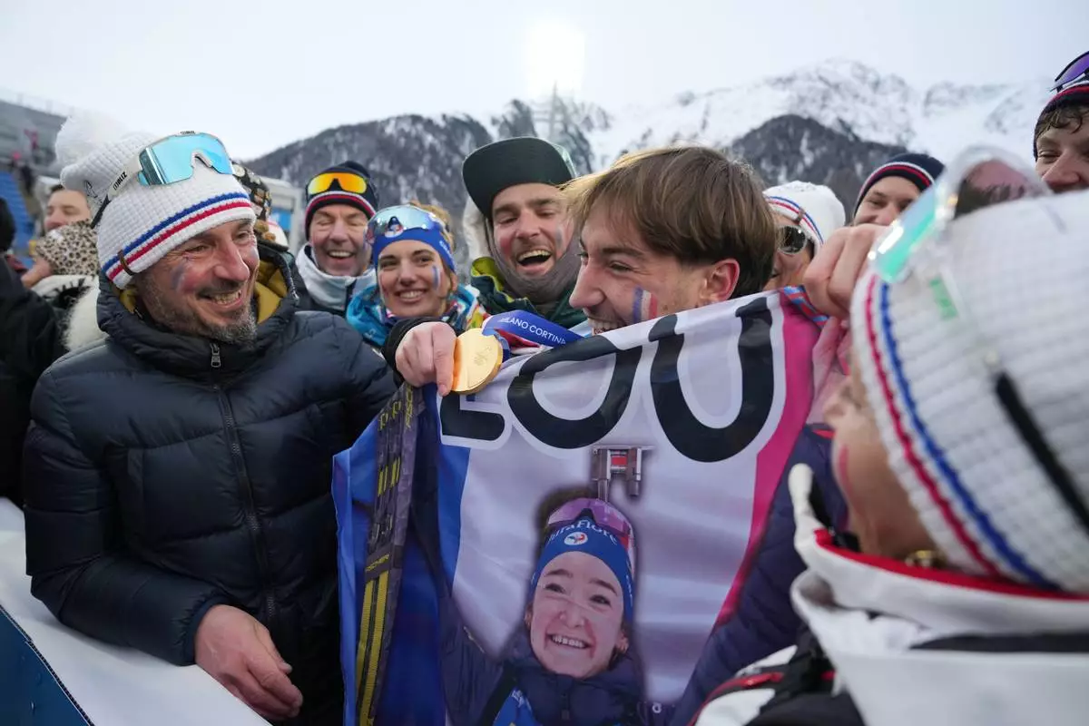 Fans of Lou Jeanmonnot, of France, hold a medal after the women's 4x6-kilometer relay biathlon race at the 2026 Winter Olympics in Anterselva, Italy, Wednesday, Feb. 18, 2026. (AP Photo/Andrew Medichini)