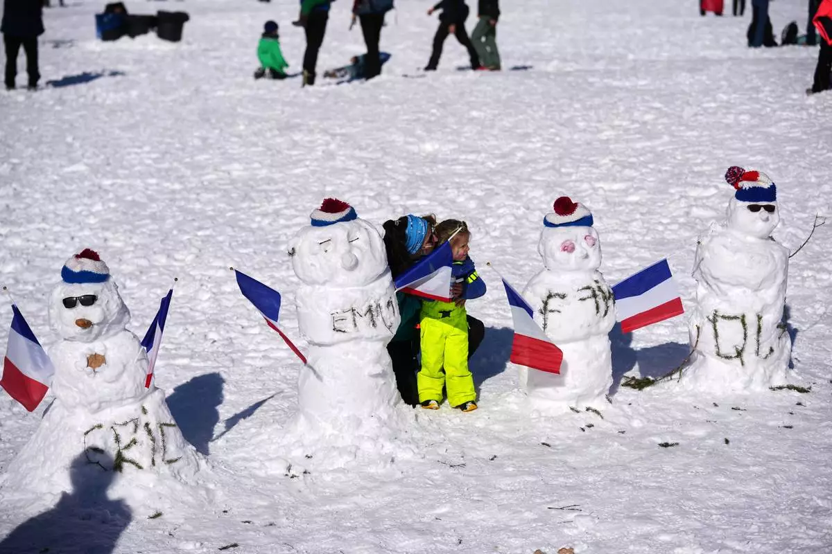 Fans take photos with snowmen with the names of France's Eric Perrot, from left, Emilien Jacquelin, Fabien Claude and Quentin Fillon Maillet ahead of the men's 15-kilometer mass start biathlon race at the 2026 Winter Olympics in Anterselva, Italy, Friday, Feb. 20, 2026. (AP Photo/Andrew Medichini)
