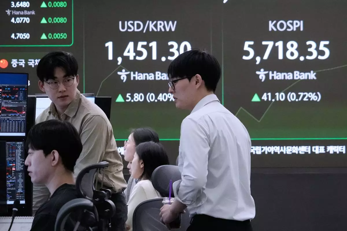 Currency traders work near a screen showing the Korea Composite Stock Price Index (KOSPI), right, and the foreign exchange rate between U.S. dollar and South Korean won at the foreign exchange dealing room of the Hana Bank headquarters in Seoul, South Korea, Friday, Feb. 20, 2026. (AP Photo/Ahn Young-joon)