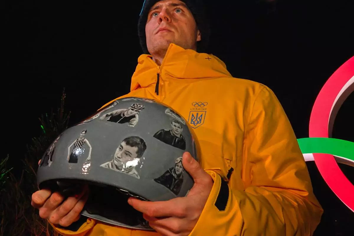 Ukraine's Vladyslav Heraskevych holds up his crash helmet during a press conference following a skeleton training session at the 2026 Winter Olympics, in Cortina d'Ampezzo, Italy, Tuesday, Feb. 10, 2026. (AP Photo/Steve Moore)