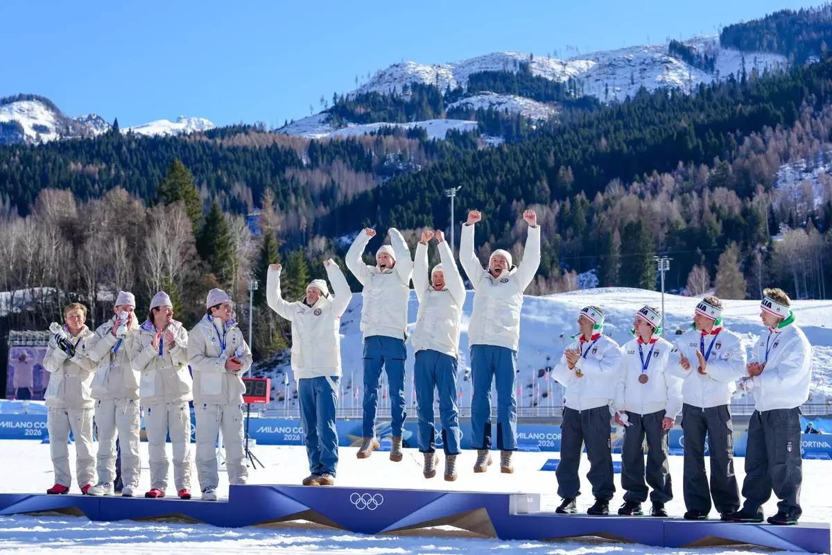 Gold medalists Norway celebrate on the podium flanked by silver medalists France, left, and bronze medalists Italy after the cross country skiing men's 4 x 7.5km relay at the 2026 Winter Olympics, in Tesero, Italy, Sunday, Feb. 15, 2026. (AP Photo/Kirsty Wigglesworth)