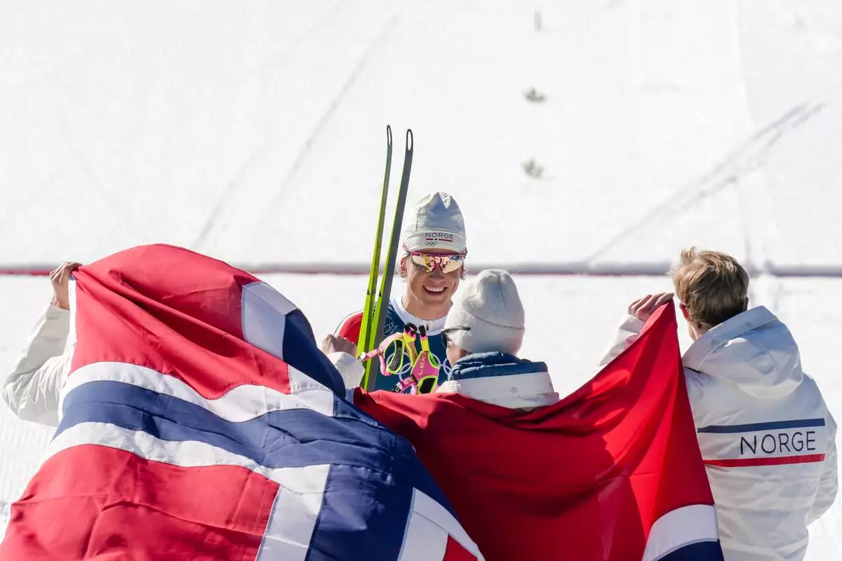 Johannes Hoesflot Klaebo, of Norway, center, joins his teammates Emil Iversen, Martin Loewstroem Nyenget and Einar Hedegart after crossing the finish line to win the gold medal in the cross country skiing men's 4 x 7.5km relay at the 2026 Winter Olympics, in Tesero, Italy, Sunday, Feb. 15, 2026. (AP Photo/Evgeniy Maloletka)