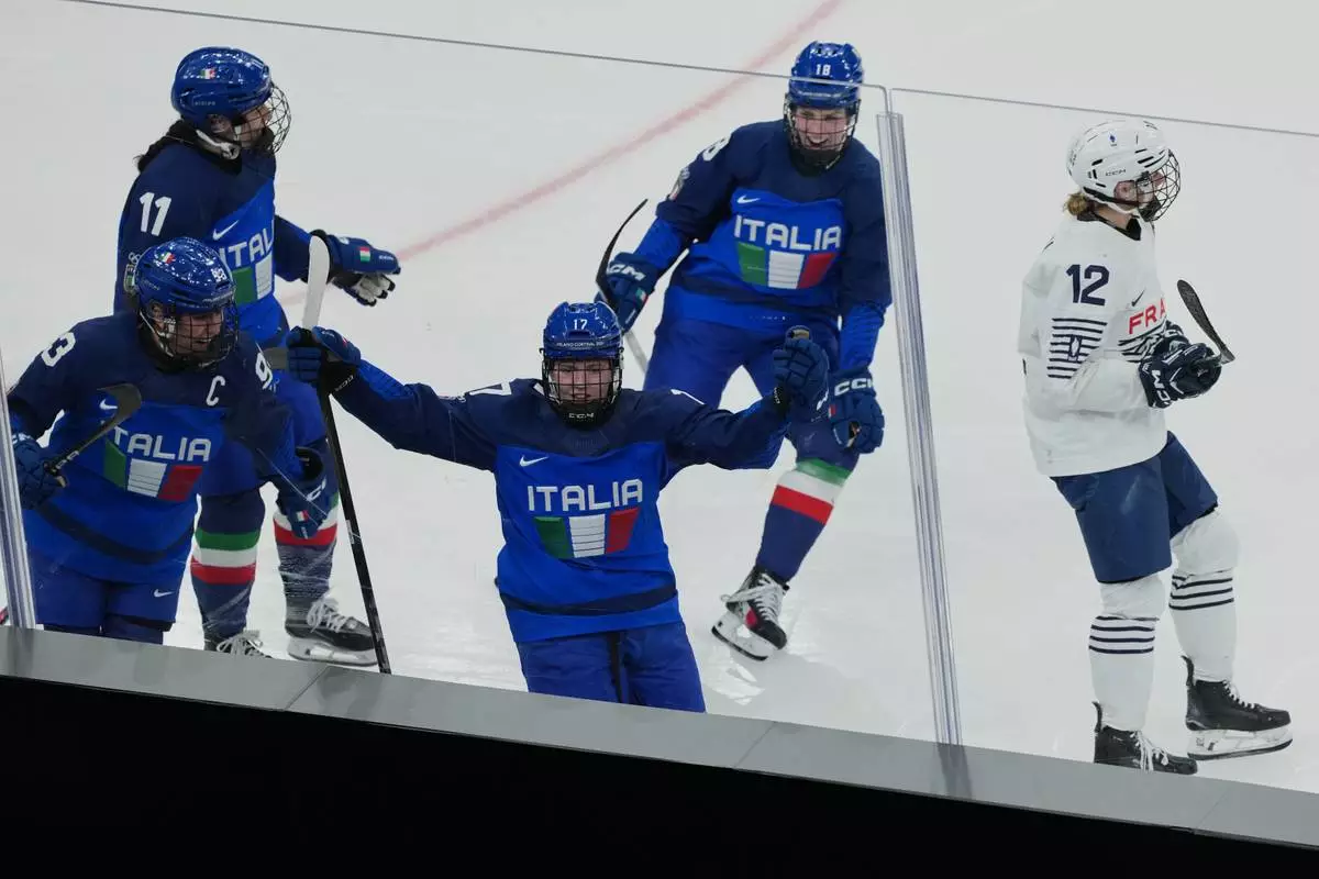 Italy's Matilde Fantin (17) celebrates scoring a goal in the third period with Italy's Nadia Mattivi (93), Italy's Justine Reyes (11), Italy's Franziska Stocker (18), as France's Estelle Duvin (12) skates away during a preliminary round match of women's ice hockey between Italy and France at the 2026 Winter Olympics, in Milan, Italy, Thursday, Feb. 5, 2026. (AP Photo/Carolyn Kaster)