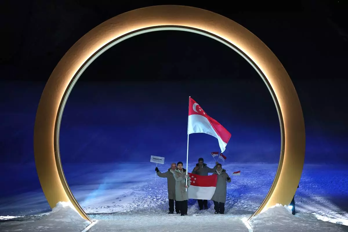 Flag bearer Faiz Basha Munwar Basha of Singapore leads the team, during the Olympic opening ceremony, at the 2026 Winter Olympics, in Livigno, Italy, Friday, Feb. 6, 2026. (Cameron Spencer, Pool Photo via AP)