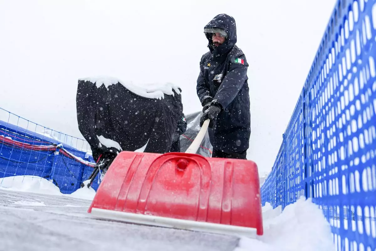 An Italian soldier shovels snow at Livigno Snow Park after men's freestyle skiing halfpipe qualifications were delayed, during the 2026 Winter Olympics, Thursday, Feb. 19, 2026, in Livigno, Italy. (AP Photo/Julia Demaree Nikhinson)