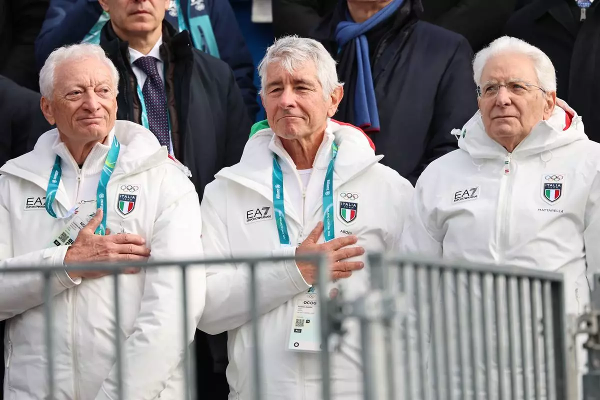 Italian President Sergio Mattarella, right, Andrea Abodi, Italian Minister for Sport and Youth, center, and Luciano Buonfiglio, President of the Italian National Olympic Committee (CONI), listen to the national anthem during the podium ceremony for an alpine ski, women's super-G race, at the 2026 Winter Olympics, in Cortina d'Ampezzo, Italy, Thursday, Feb. 12, 2026. (AP Photo/Marco Trovati)