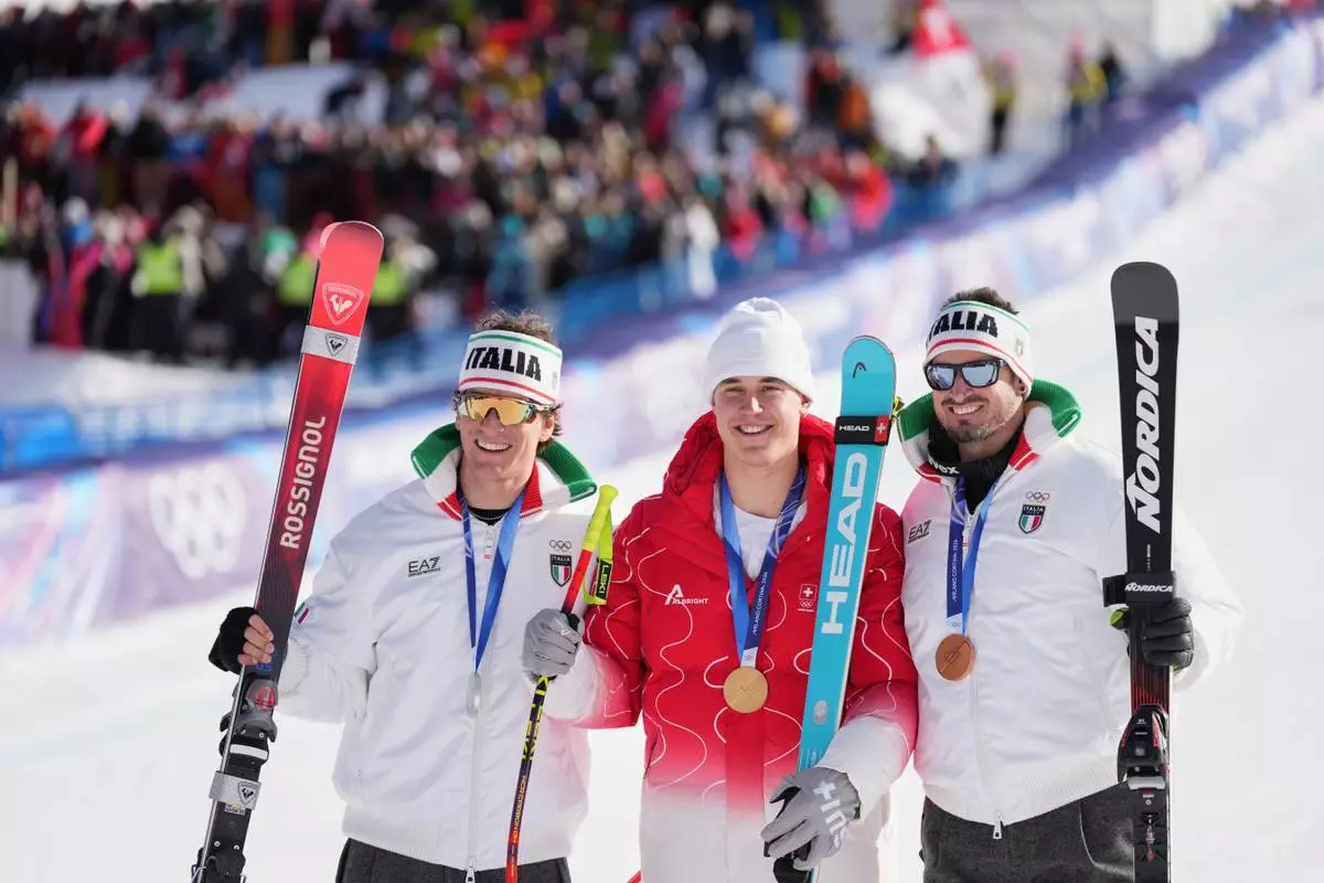 Switzerland's Franjo von Allmen, gold medal in an alpine ski men's downhill race, center, celebrates with silver medalist Italy's Giovanni Franzoni, left, and bronze medalist Italy's Dominik Paris at the 2026 Winter Olympics, in Bormio, Italy, Saturday, Feb. 7, 2026. (AP Photo/Rebecca Blackwell)