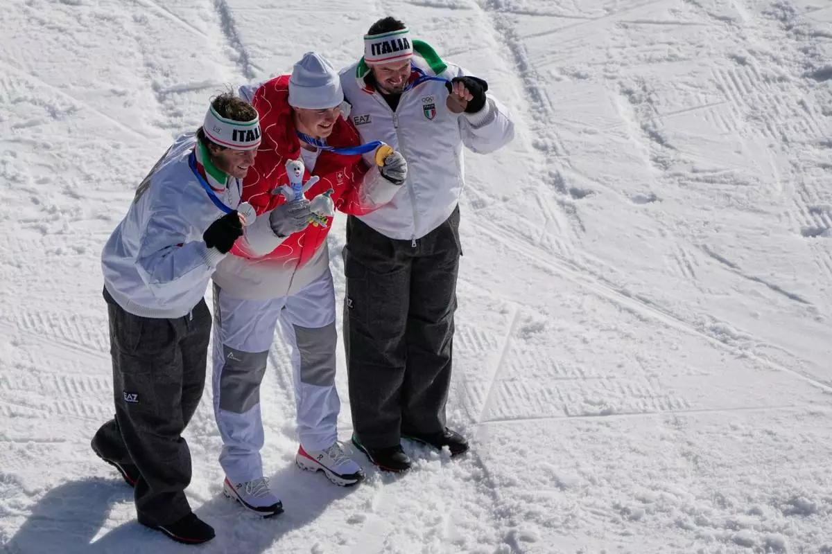 Switzerland's Franjo von Allmen, center, gold, Italy's Giovanni Franzoni, left, silver, and Italy's Dominik Paris, bronze, pose after an alpine ski, men's downhill race, at the 2026 Winter Olympics, in Bormio, Italy, Saturday, Feb. 7, 2026. (AP Photo/John Locher)