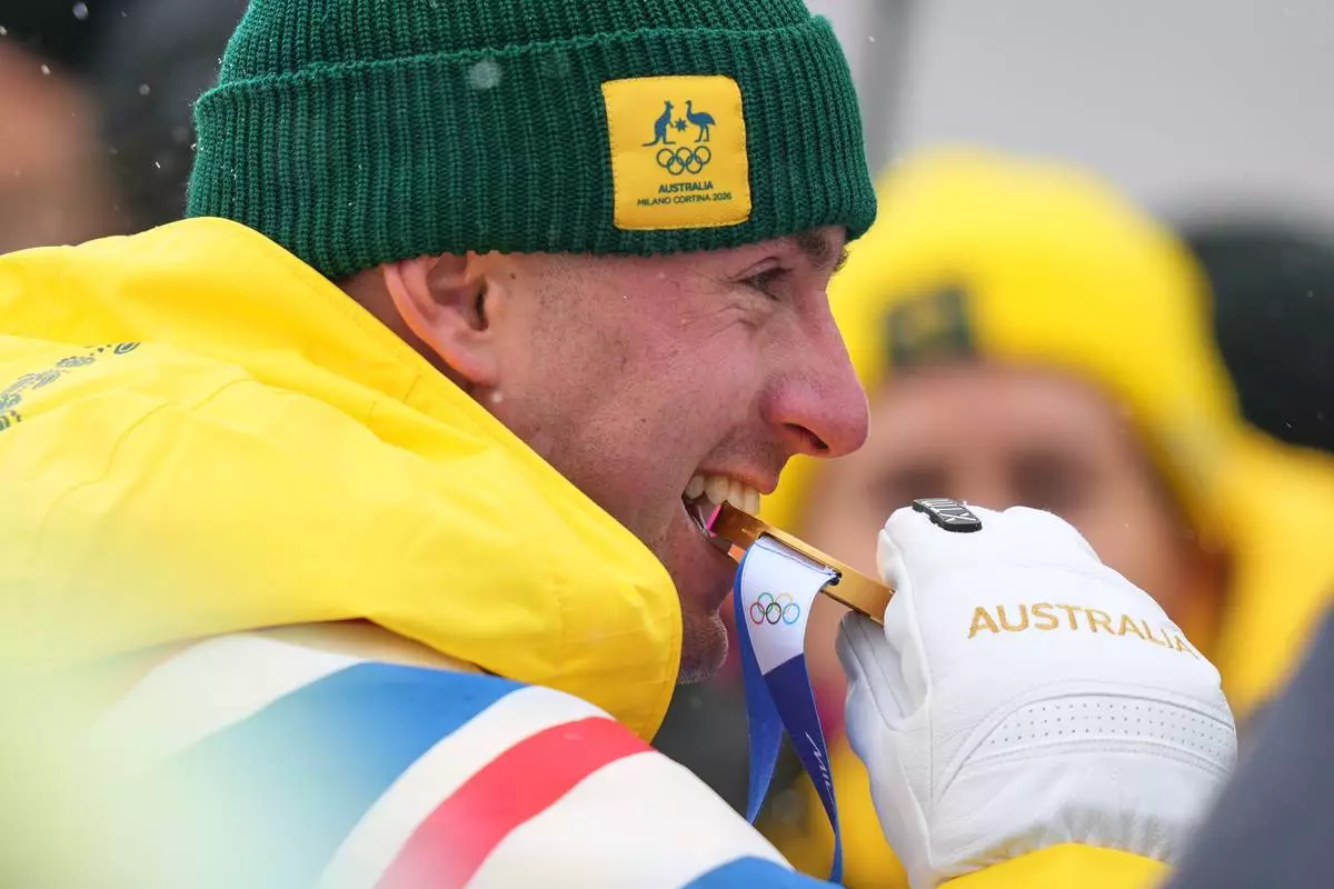 Australia's Cooper Woods bites his gold medal after the men's freestyle skiing moguls finals at the 2026 Winter Olympics, in Livigno, Italy, Thursday, Feb. 12, 2026. (AP Photo/Abbie Parr)