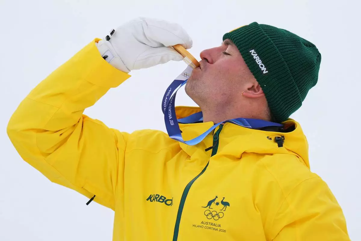 Australia's Cooper Woods kisses his gold medal after the men's freestyle skiing moguls finals at the 2026 Winter Olympics, in Livigno, Italy, Thursday, Feb. 12, 2026. (AP Photo/Abbie Parr)