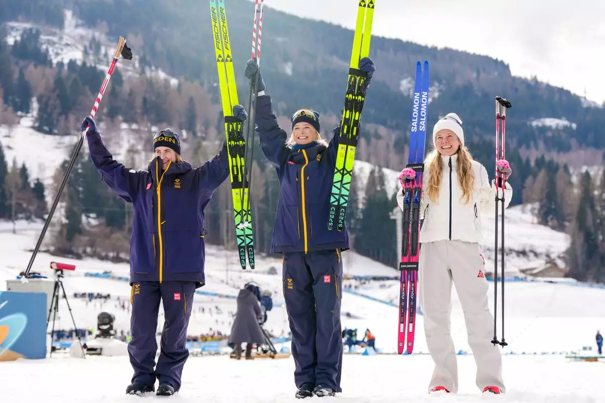 Silver medalist Ebba Andersson, of Sweden, from left, gold medalist Frida Karlsson, of Sweden, and bronze medalist Jessie Diggins, of the United States, pose after finishing the cross country skiing women's 10km interval start free at the 2026 Winter Olympics, in Tesero, Italy, Thursday, Feb. 12, 2026. (AP Photo/Kirsty Wigglesworth)