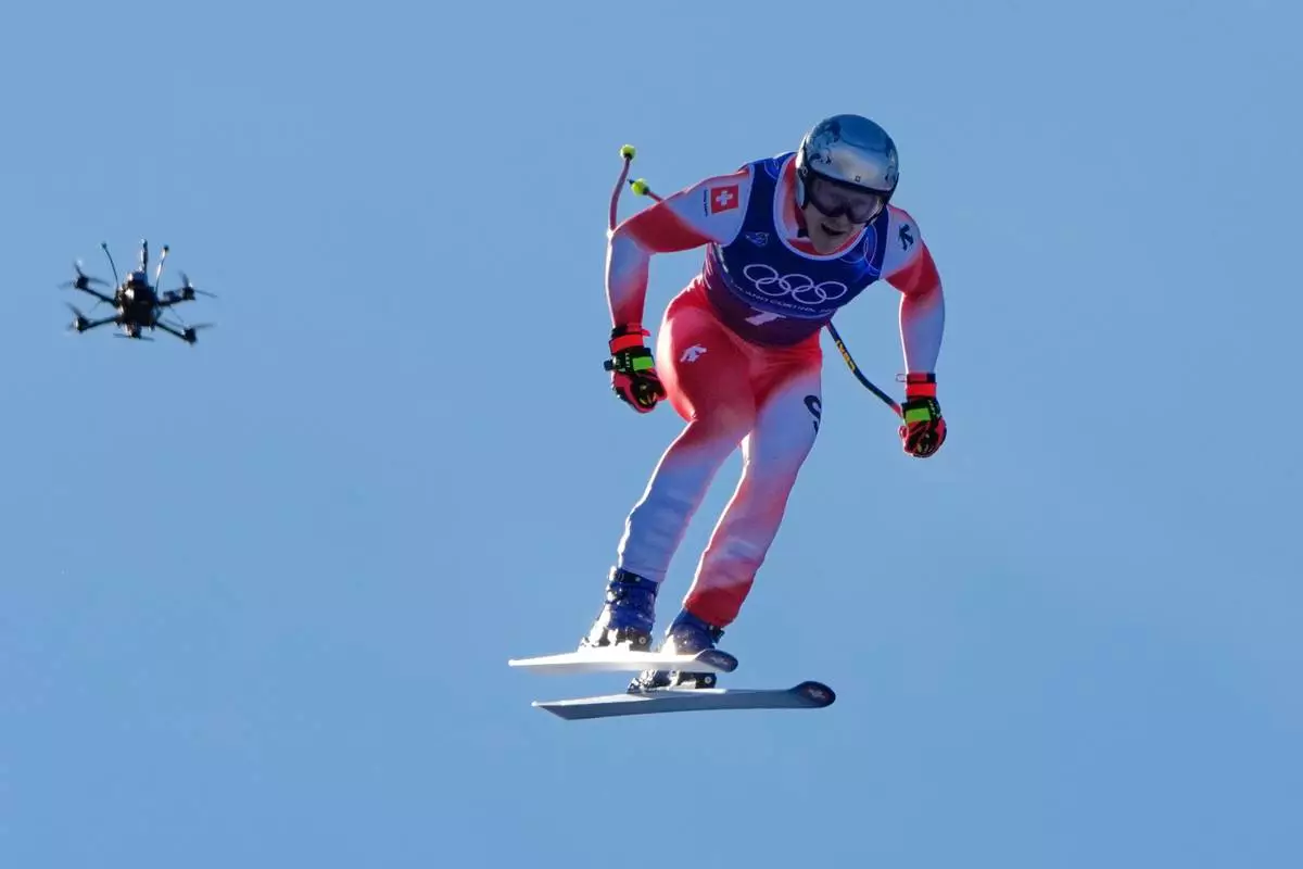 Switzerland's Marco Odermatt, flanked by a drone, speeds down the course of an alpine ski men's downhill portion of a team combined race, at the 2026 Winter Olympics, in Bormio, Italy, Monday, Feb. 9, 2026. (AP Photo/John Locher)