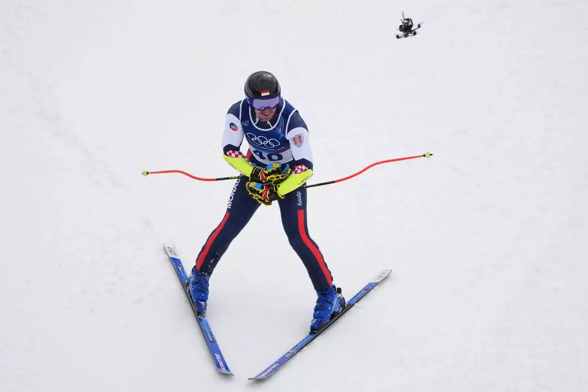 A drone flies above Monaco's Arnaud Alessandria during an alpine ski, men's super-G race, at the 2026 Winter Olympics, in Bormio, Italy, Wednesday, Feb. 11, 2026. (AP Photo/Rebecca Blackwell)