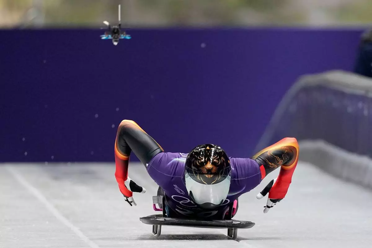 A drone follows China's Lin Qinwei as he starts for a men's skeleton training session at the 2026 Winter Olympics, in Cortina d'Ampezzo, Italy, Tuesday, Feb. 10, 2026. (AP Photo/Aijaz Rahi)