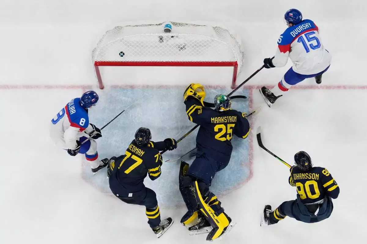 Slovakia's Dalibor Dvorsky, right, scores his side's third goal during a preliminary round game of men's ice hockey between Sweden and Slovakia at the 2026 Winter Olympics, in Milan, Italy, Saturday, Feb. 14, 2026. (AP Photo/Hassan Ammar)