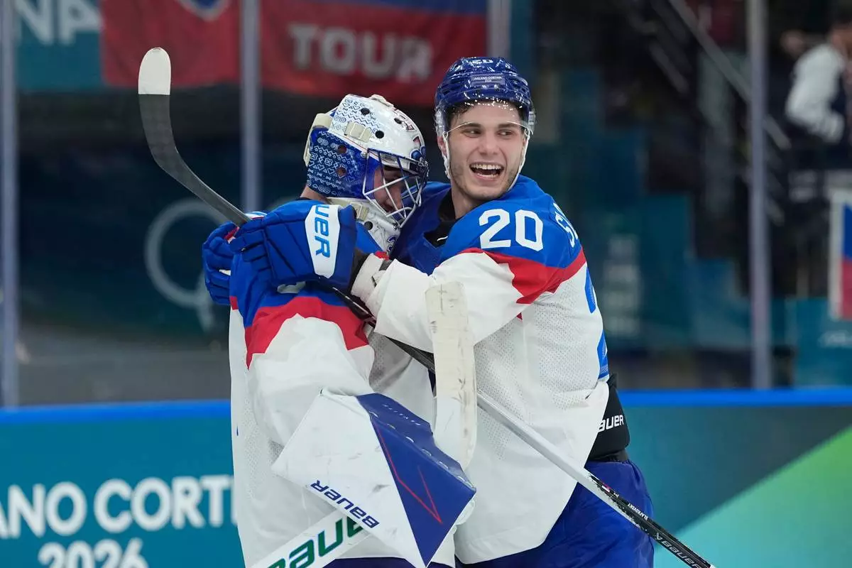 Slovakia's goalkeeper Samuel Hlavaj, left, celebrates with his teammate Slovakia's Juraj Slafkovsky end of a preliminary round match of men's ice hockey between Sweden and Slovakia at the 2026 Winter Olympics, in Milan, Italy, Saturday, Feb. 14, 2026. (AP Photo/Petr David Josek)