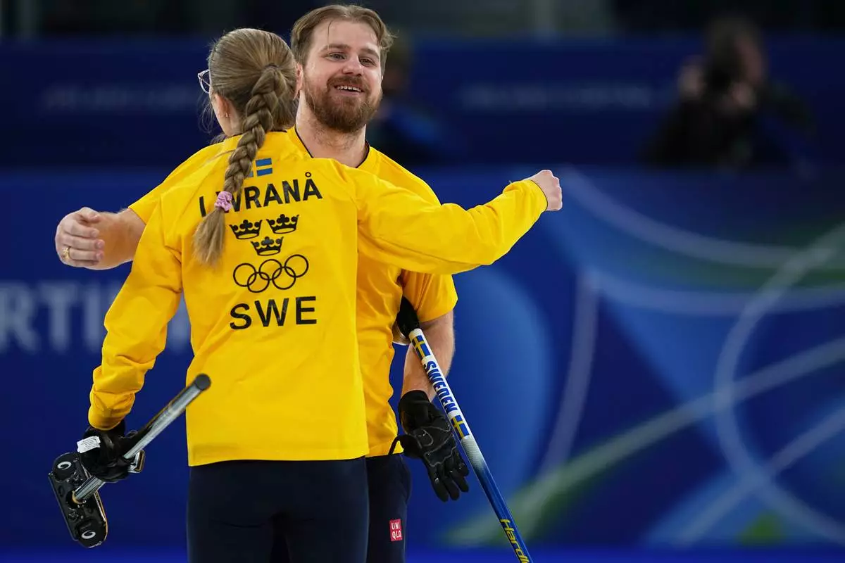 Sweden's Rasmus Wranaa hugs Isabella Wranaa during the semi-finals round of the mixed doubles curling match against Britain, at the 2026 Winter Olympics, in Cortina d'Ampezzo, Italy, Monday, Feb. 9, 2026. (AP Photo/Fatima Shbair)