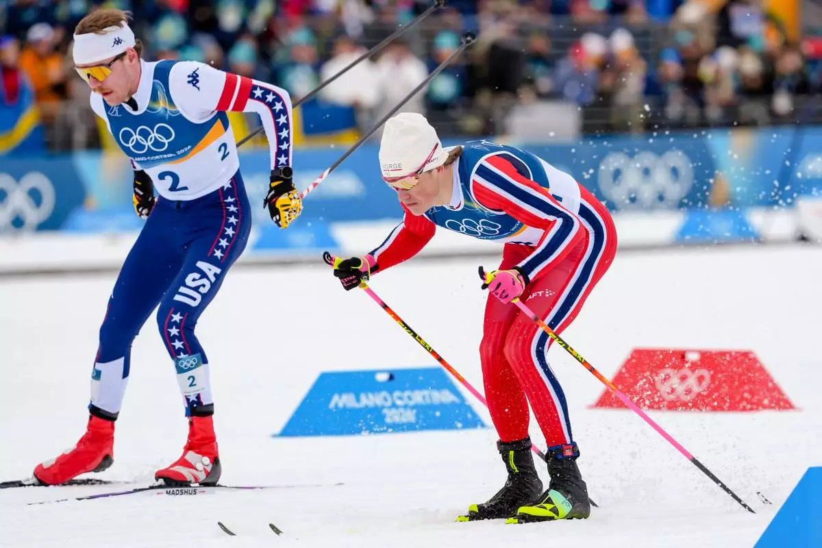 Ben Ogden, of the United States, left, and Johannes Hoesflot Klaebo, right, compete in the cross-country skiing men's sprint classic at the 2026 Winter Olympics, in Tesero, Italy, Tuesday, Feb. 10, 2026. (AP Photo/Kirsty Wigglesworth)