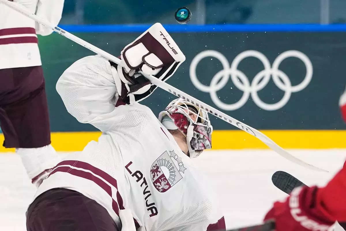 Latvia's goalkeeper Arturs Silovs makes a save during a preliminary round match of men's ice hockey between Denmark and Latvia at the 2026 Winter Olympics, in Milan, Italy, Sunday, Feb. 15, 2026. (AP Photo/Petr David Josek)
