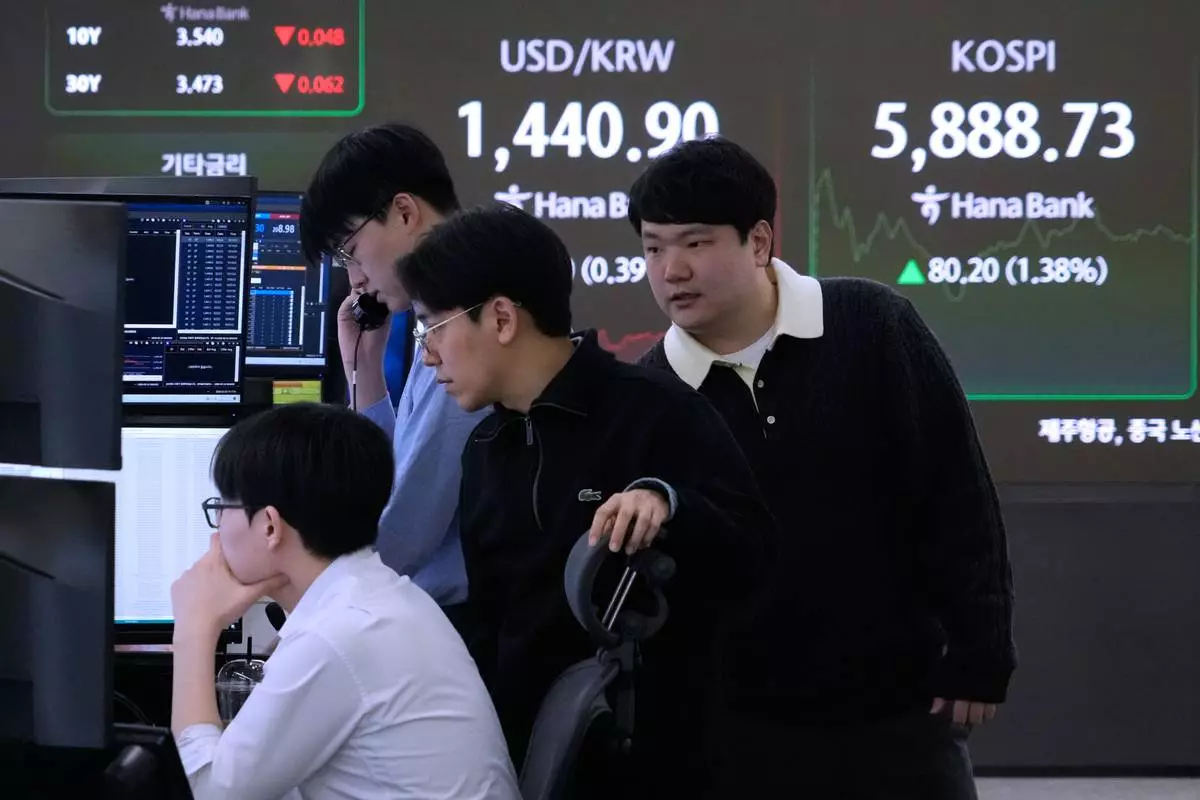 Currency traders watch monitors near a screen showing the Korea Composite Stock Price Index (KOSPI), top right, and the foreign exchange rate between U.S. dollar and South Korean won at the foreign exchange dealing room of the Hana Bank headquarters in Seoul, South Korea, Monday, Feb. 23, 2026. (AP Photo/Ahn Young-joon)