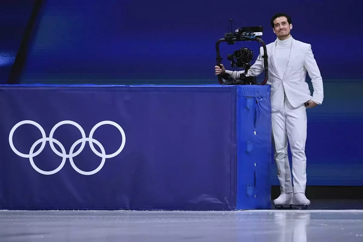 Jordan Cowan operates the steadicam before the pairs figure skating short program at the 2026 Winter Olympics, in Milan, Italy, Sunday, Feb. 15, 2026. (AP Photo/Ashley Landis)