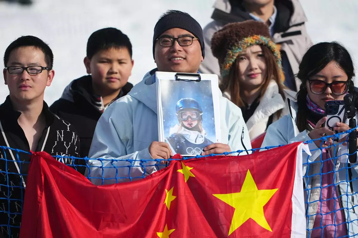 A fan holds a photo of China's Eileen Gu before the women's freestyle skiing halfpipe final at the 2026 Winter Olympics, in Livigno, Italy, Sunday, Feb. 22, 2026. (AP Photo/Lindsey Wasson)