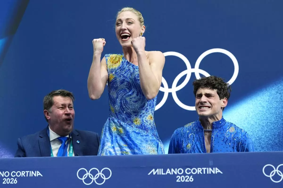 Piper Gilles, center, and Paul Poirier, right, of Canada react to their scores after competing during the ice dancing free skate in figure skating at the 2026 Winter Olympics, in Milan, Italy, Wednesday, Feb. 11, 2026. (AP Photo/Stephanie Scarbrough)