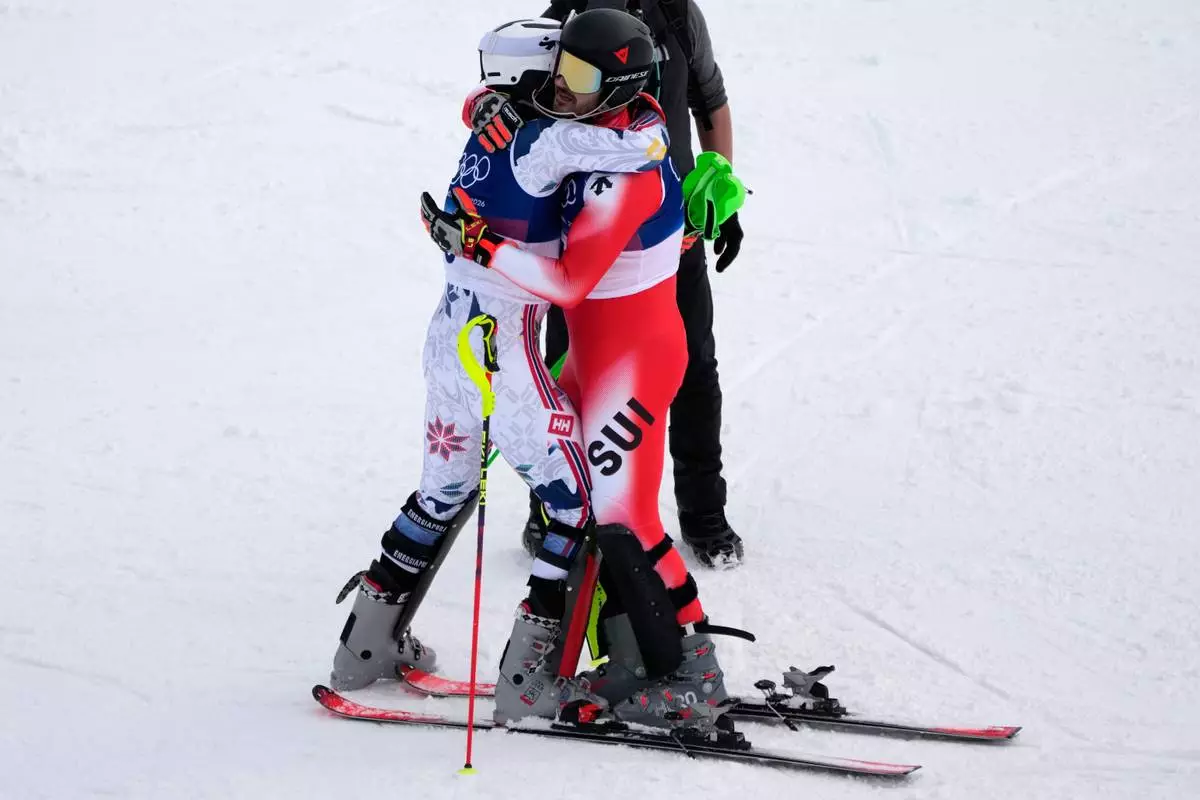 Norway's Henrik Kristoffersen, left, hugs Switzerland's Loic Meillard at the finish area, during an alpine ski, men's slalom race, at the 2026 Winter Olympics, in Bormio, Italy, Monday, Feb. 16, 2026. (AP Photo/John Locher)