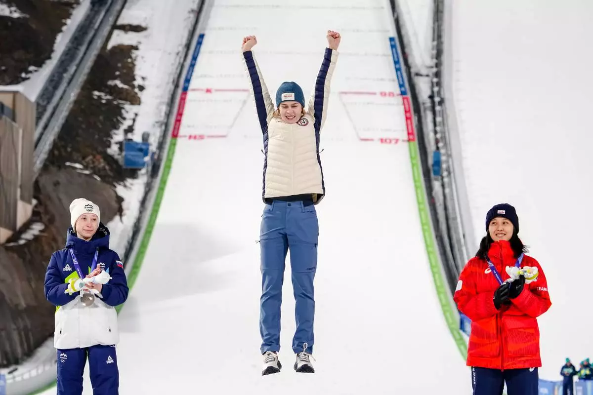 Gold medalist Anna Odine Stroem, of Norway, celebrates flanked by silver medalist Nika Prevc, of Slovenia, left, and bronze medalist Nozomi Maruyama, of Japan, on the podium of the ski jumping women's normal hill individual, at the 2026 Winter Olympics, in Predazzo, Italy, Saturday, Feb. 7, 2026. (AP Photo/Kirsty Wigglesworth)