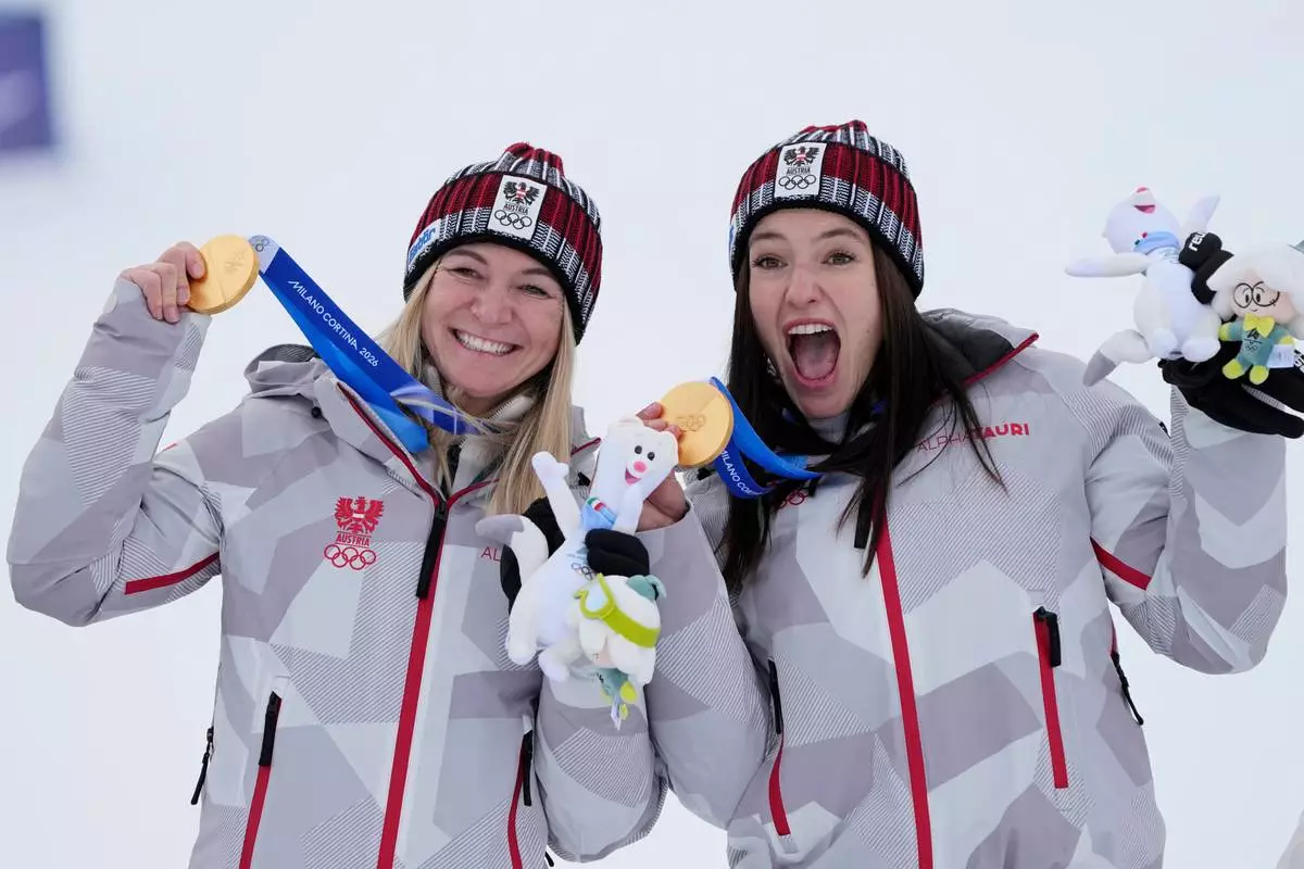 Austria's Ariane Raedler, left, and teammate Austria's Katharina Huber show their gold medals in an alpine ski, women's team combined race, at the 2026 Winter Olympics, in Cortina d'Ampezzo, Italy, Tuesday, Feb. 10, 2026. (AP Photo/Andy Wong)