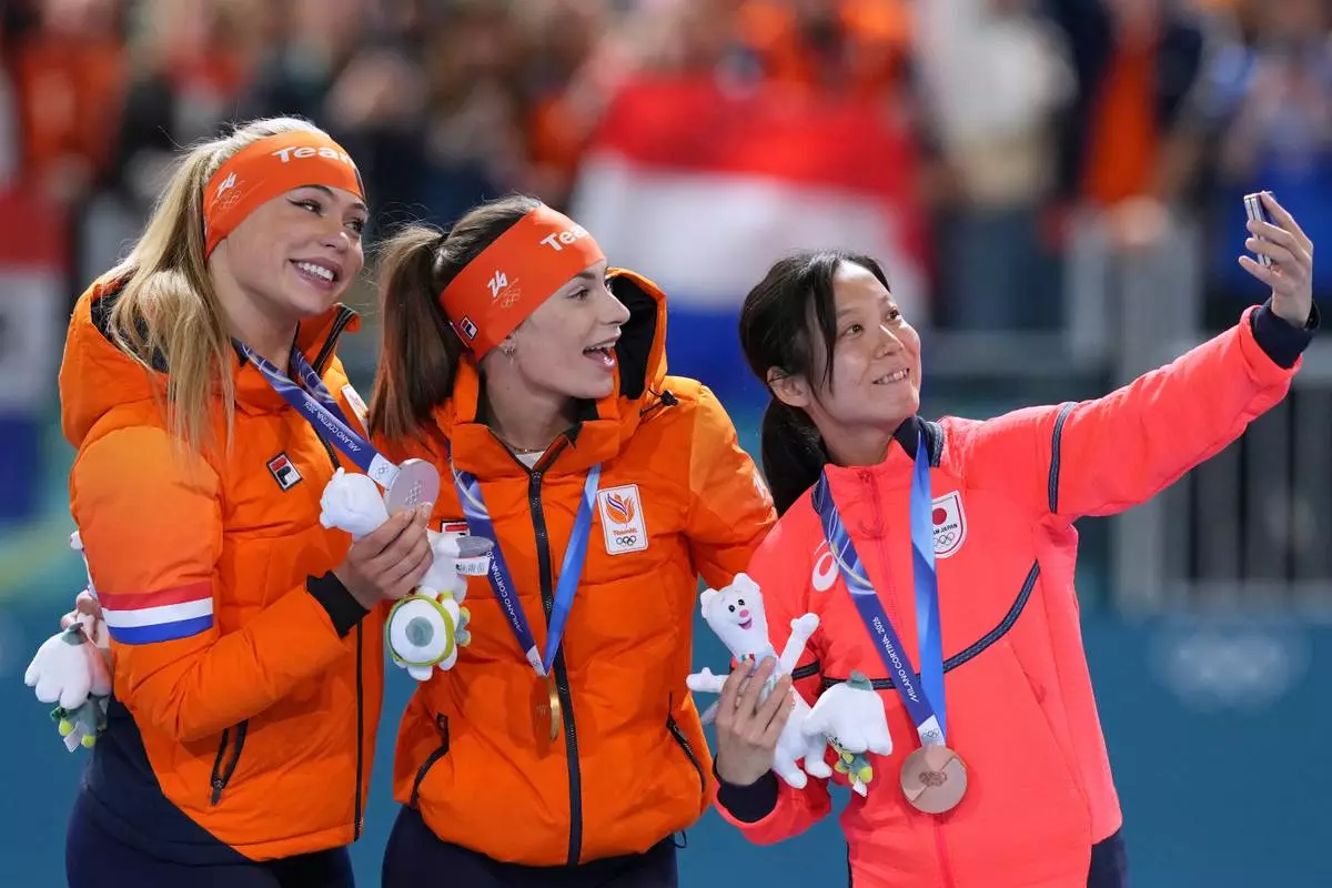 Femke Kok of the Netherlands, center and gold medal, Jutta Leerdam of the Netherlands, left and silver medal, and Miho Takagi of Japan, right and bronze medal, celebrate on the podium of the women's 500 meters speedskating race at the 2026 Winter Olympics, in Milan, Italy, Sunday, Feb. 15, 2026. (AP Photo/Antonio Calanni)