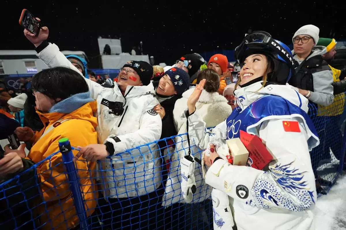 China's Eileen Gu takes photos with attendees after the women's freestyle skiing halfpipe qualifications at the 2026 Winter Olympics, in Livigno, Italy, Thursday, Feb. 19, 2026. (AP Photo/Lindsey Wasson)
